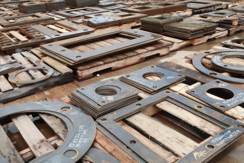 Stacks of custom cut steel plates and ring flanges with bolt holes, cut at Madden Bolt.