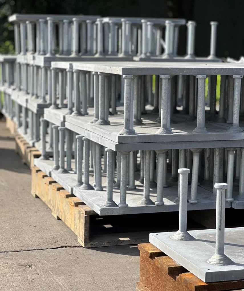 Hot-dip galvanized steel embed plates with headed stud anchors stacked on pallets.
