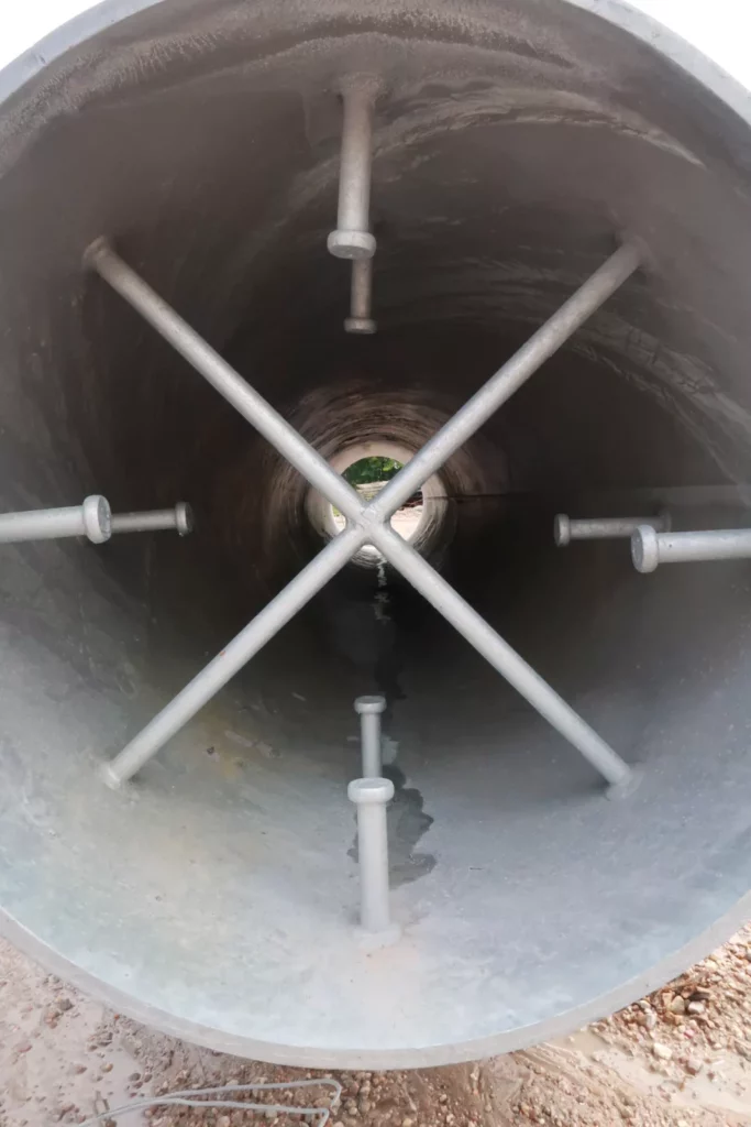 View through a large galvanized pipe sleeve embed showing cross-rod bracing