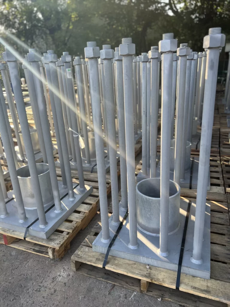 Galvanized embed plate assemblies with pipe sleeves and anchor bolts palletized for shipping