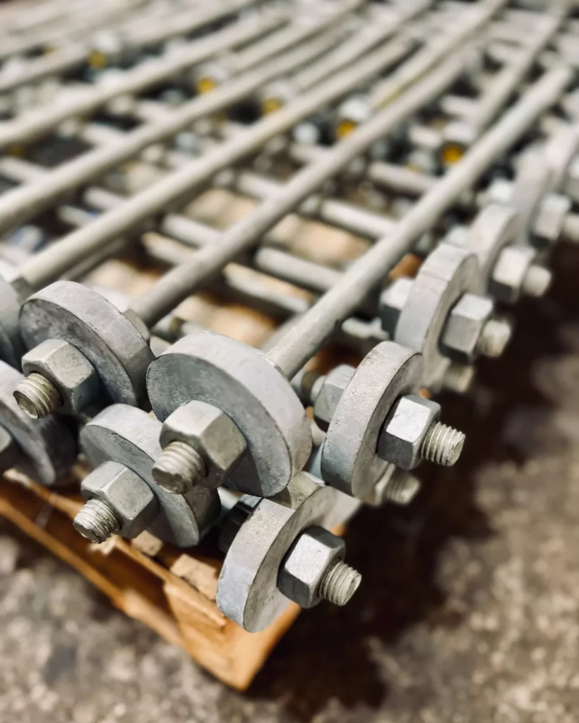 Close-up of hot-dip galvanized anchor bolts with square plate washers and heavy hex nuts.