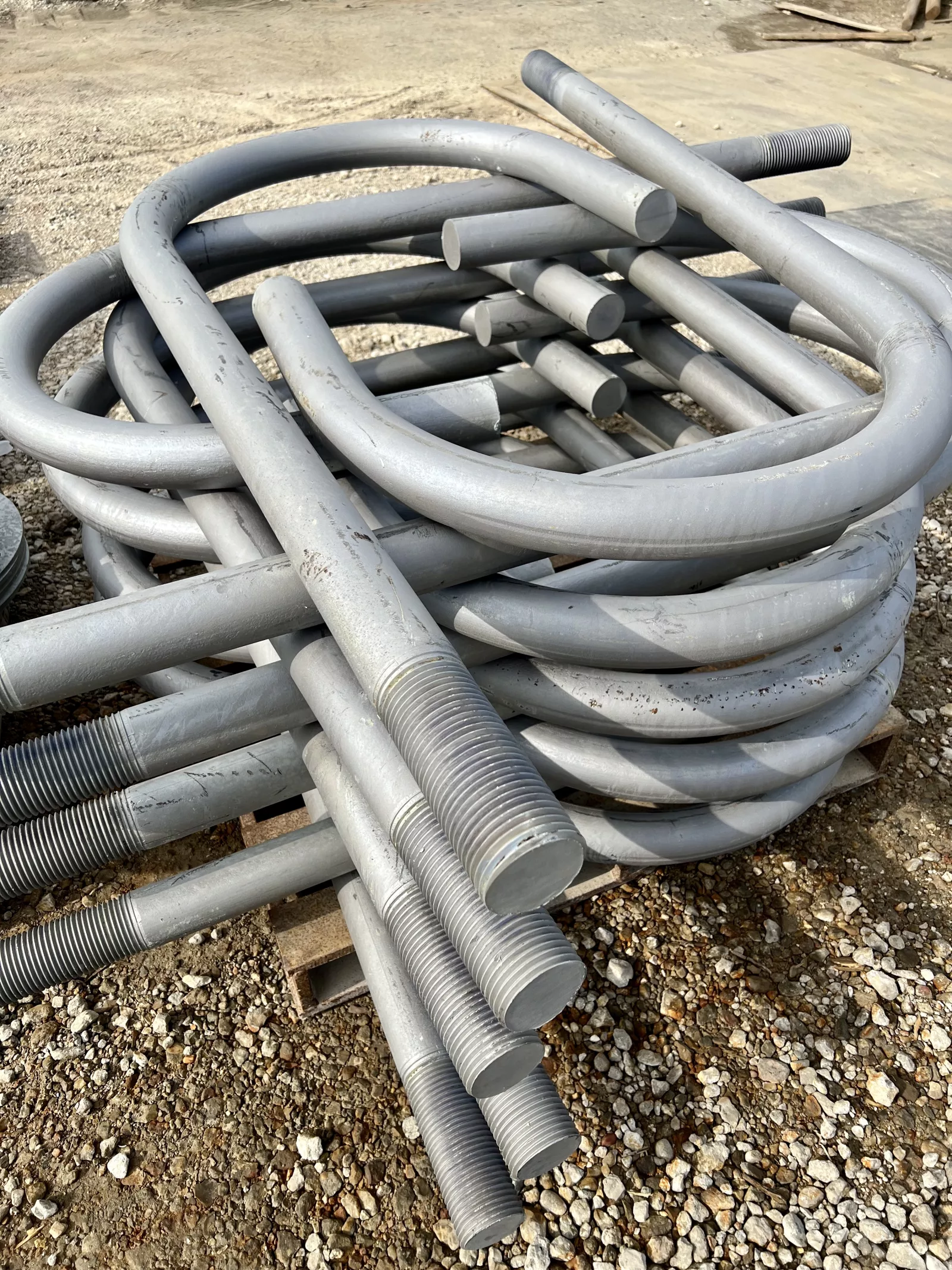 Stack of hot-dip galvanized 3-inch J-type anchor bolts staged in the yard.