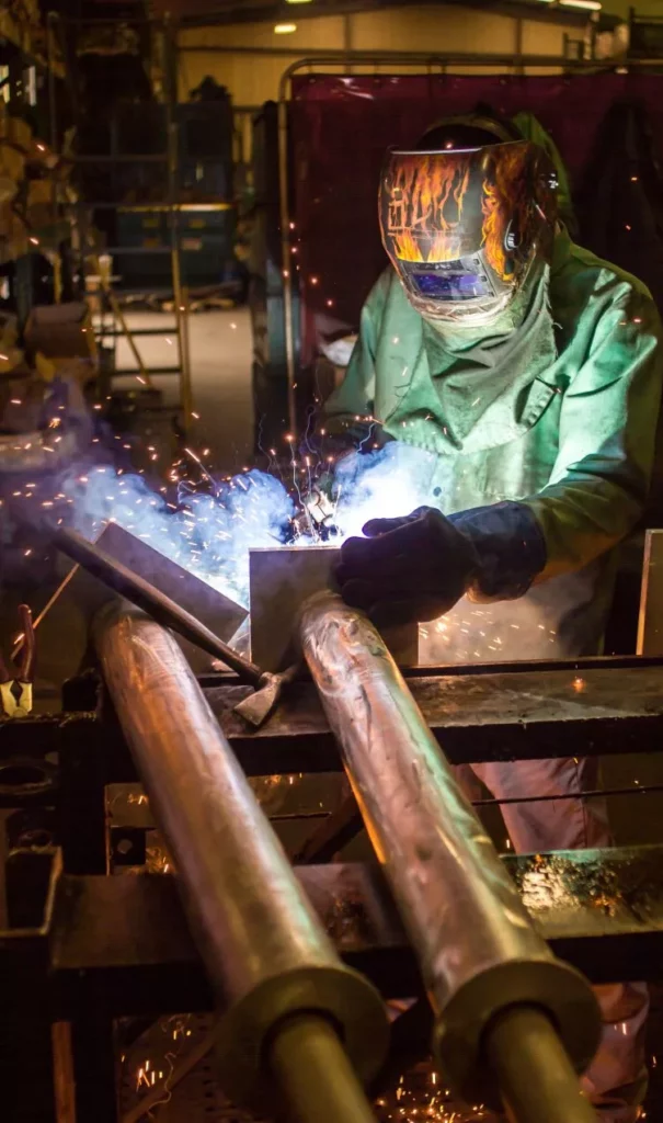 Madden Bolt welder in protective gear welding a steel assembly with sparks flying in the Houston fabrication shop.