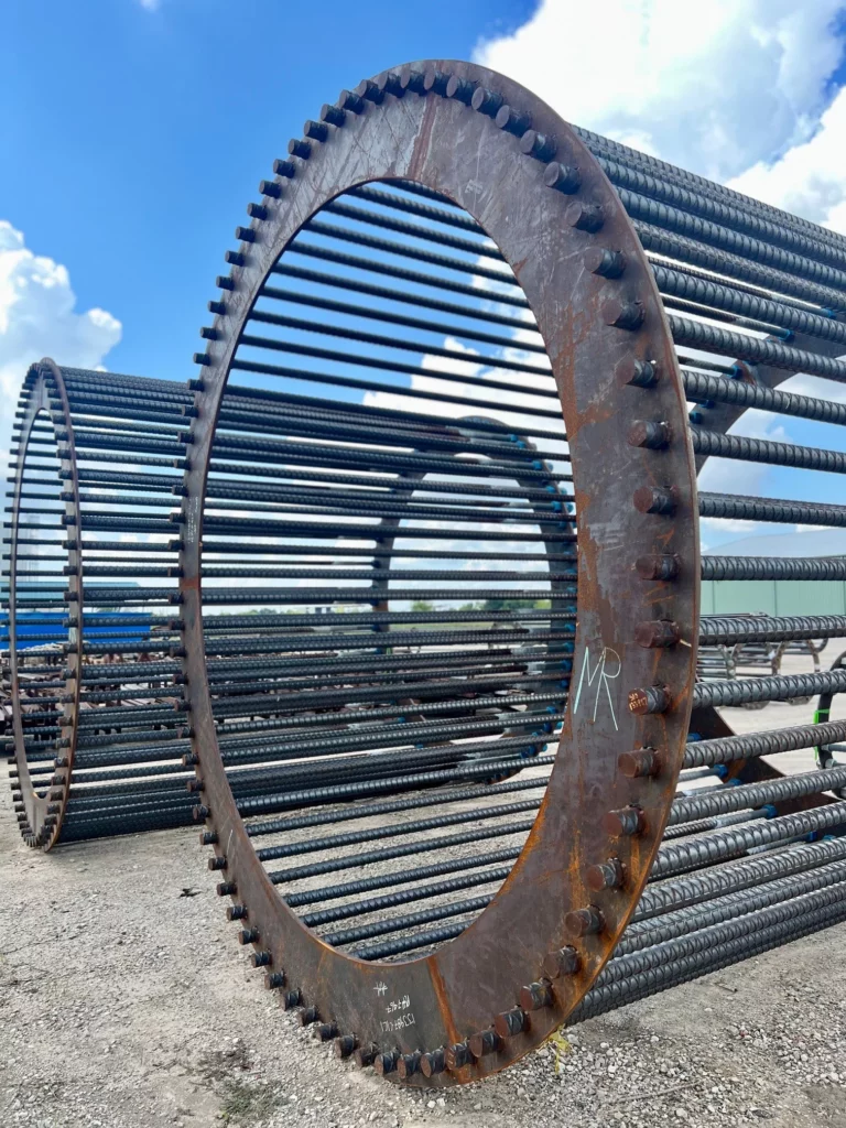 Large wide-OD rebar anchor cage with a heavy bolted steel ring flange under a blue sky.
